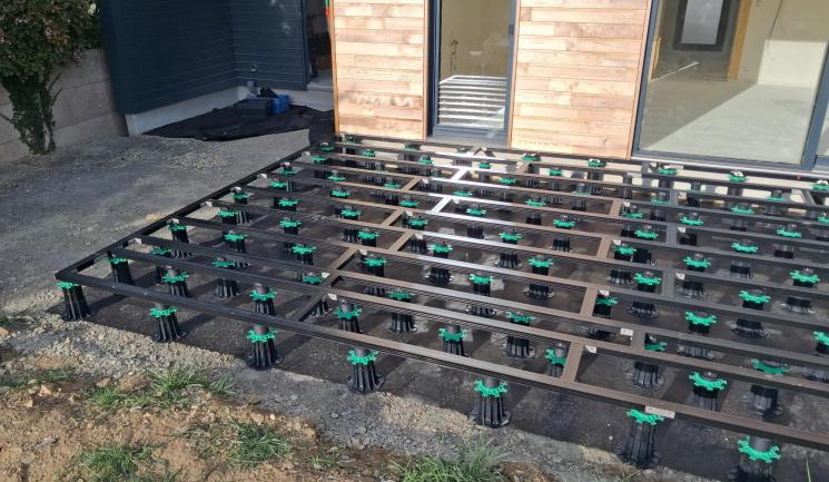 Lambourdes aluminium Réversil posées sur plots réglables devant une maison à bardage bois